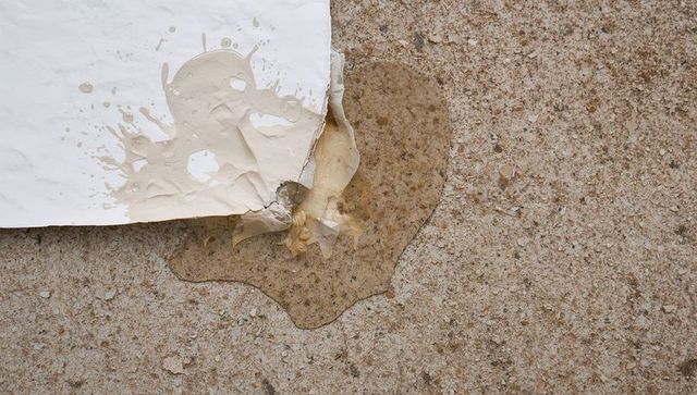 Torn paper soaking beige paste on concrete with crumpled translucent plastic film and stain texture