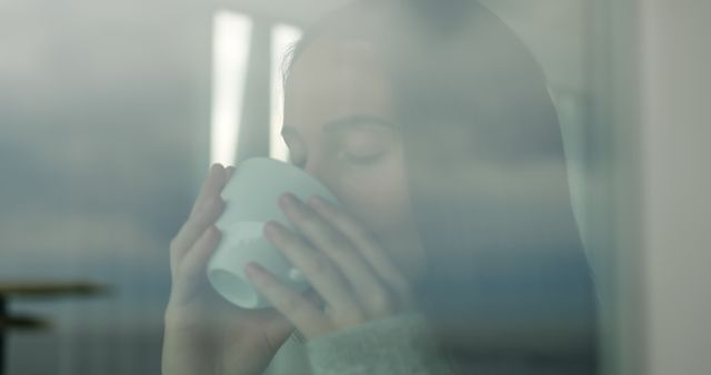 Reflective Young Woman Enjoying Hot Beverage by Window - Download Free Stock Images Pikwizard.com