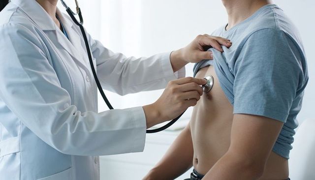 Doctor listening to male patient chest with stethoscope for heart and lung exam