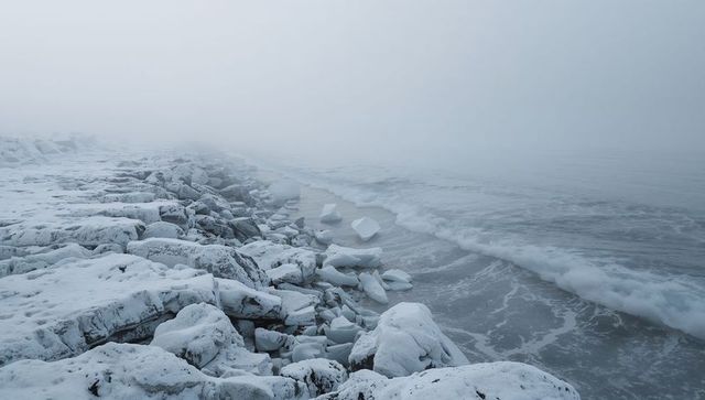 Foggy Arctic Coastline with Snow-Covered Breakwater, Fractured Ice and Foamy Waves