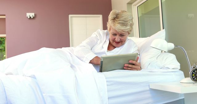 Smiling Senior Woman Using Tablet in Bed at Home - Download Free Stock Images Pikwizard.com