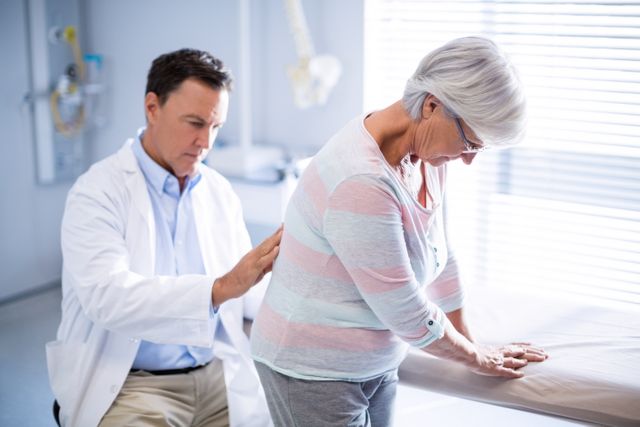 Senior woman receiving back pain treatment from physiotherapist in a clinic. Ideal for use in healthcare, medical, and wellness contexts, showcasing patient care, physical therapy, and rehabilitation services.
