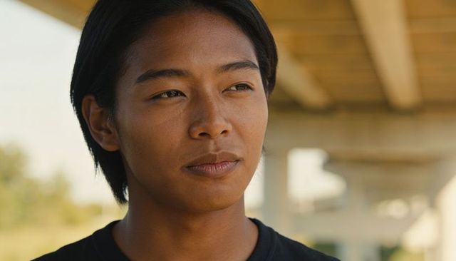 Thoughtful teenage male standing under concrete overpass headshot with warm natural light