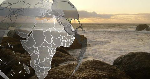 Faint globe overlay showing africa coastline at sunset over rocky seascape, choppy waves