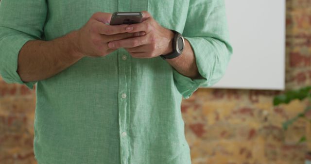 Casual man in green shirt using smartphone - Download Free Stock Images Pikwizard.com