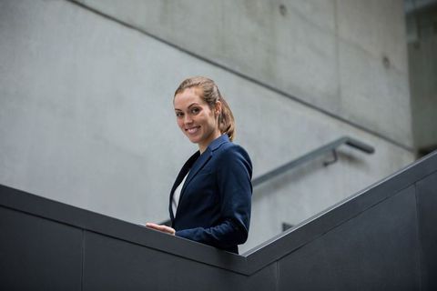 Businesswoman Smiling on Modern Office Staircase