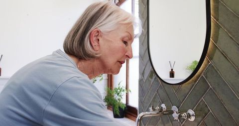 Senior woman embracing daily self-care routine in serene bathroom