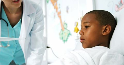 Doctor consulting worried child in pediatric hospital bed showing chart and care plan