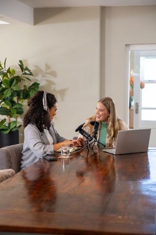 Diverse female coworkers recording podcast in casual office setting