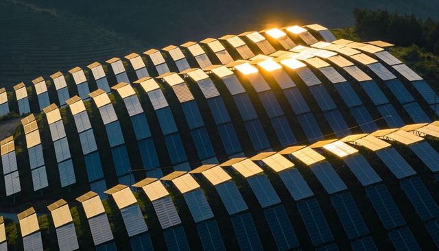 Terraced solar farm forming shimmering wave patterns and reflective panels on sunlit hillside