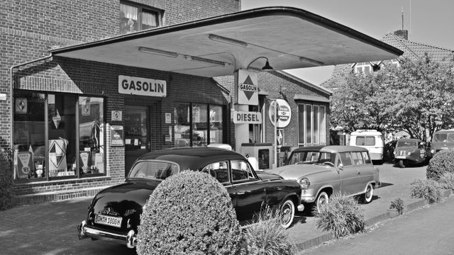 This vintage gasoline station scene features classic cars from the 1950s in a monochromatic black and white setting. Ideal for use in articles or marketing materials related to automotive history, retro lifestyles, vintage trends, and nostalgic themes. Great for decorating modern spaces with a classic touch, illustrating historical documentaries, or conveying a sense of nostalgia in publications.