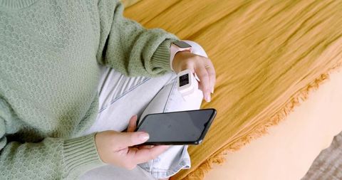 Woman Relaxing with Smartphone and Smartwatch in Cozy Home Setting