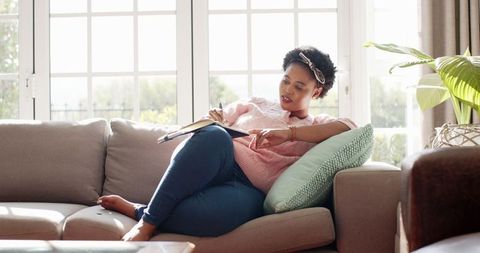 Afro-American Woman Relaxing with Book on Cozy Sofa at Home - Download Free Stock Images Pikwizard.com