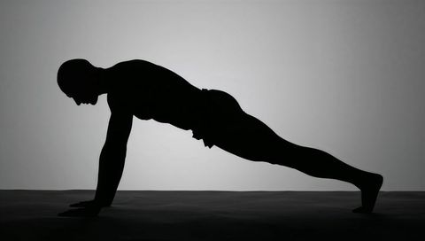 Silhouette Man Holding Plank Exercise Performing Core Strength Training in Studio