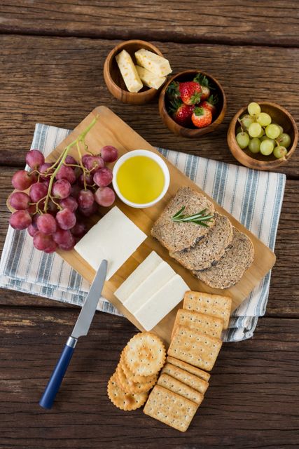 Gouda cheese, brown bread slices, lime juice biscuits and fruits on wooden table