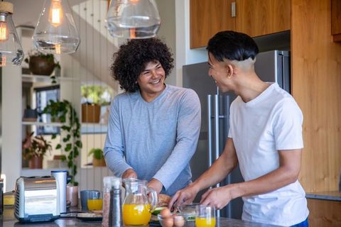 Joyful male couple preparing breakfast in modern kitchen