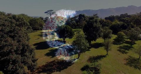 Translucent holographic face hovering over sunlit park meadow casting pixel glow