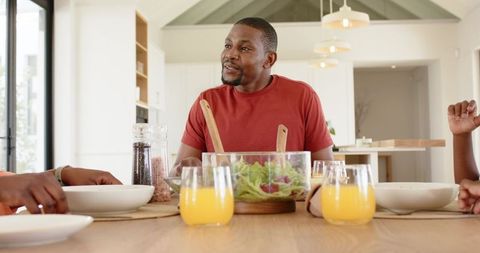 African american family enjoying bright modern kitchen breakfast, father tossing salad