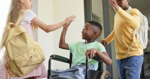 Children exchanging high fives around wheelchair, promoting inclusion and teamwork