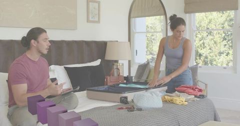 Couple packing suitcase together in cozy bedroom preparing for weekend trip