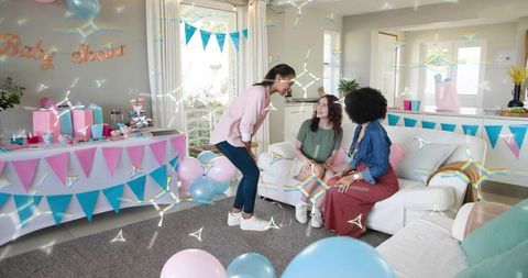 Pastel baby shower celebration with friends chatting on sofa, balloons, cake and gifts