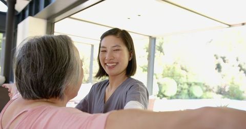 Caregiver assisting senior woman with home therapy