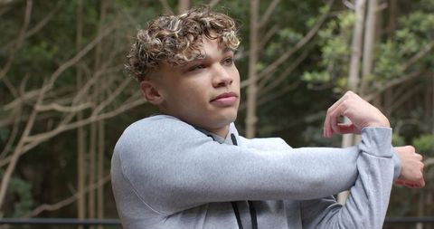 Young Man Stretching in Park for Warm-Up Exercise