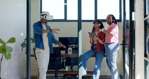Diverse team testing virtual reality interface collaborating with tablet in sunlit office
