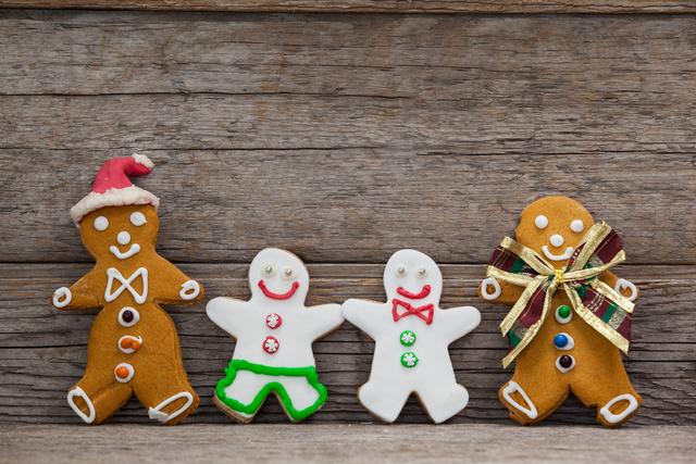 Various gingerbread cookies decorated with colorful frosting and details, propped against rustic wooden planks. Ideal for holiday-themed designs, Christmas promotions, baking blogs, or festive greeting cards.