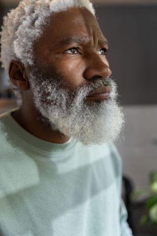 Thoughtful african american senior man gazing upward in soft light closeup portrait