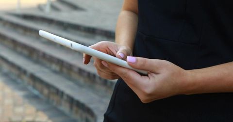 Woman Engaging with Tablet Outdoors on Stone Steps