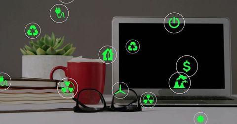 Arranging minimalist workspace with silver laptop, red mug and green sustainability icons