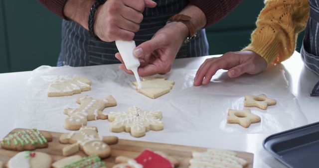 People are seen decorating Christmas-themed cookies with icing. Picture highlights the close-up of hands while decorating cookies. Use image for holiday baking promotions, festive recipe blogs, or family activity guides for Christmas season.