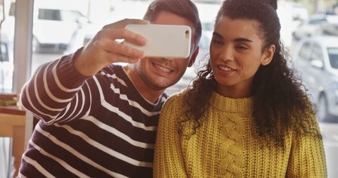 Smiling Couple Taking Selfie in Casual Cafe Setting