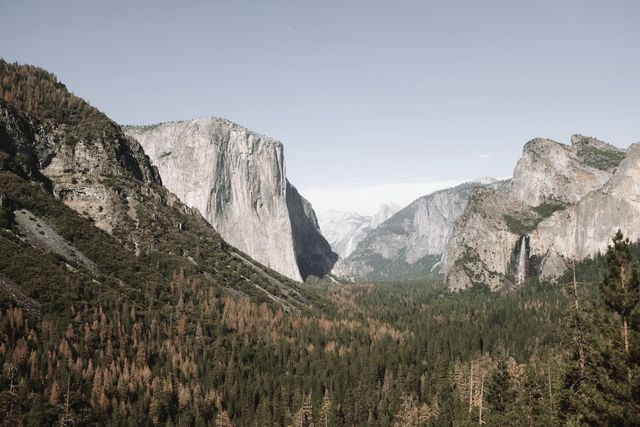 Majestic view of Yosemite Valley featuring the iconic El Capitan rock formation and vast forests. Ideal for travel articles, nature documentaries, tourism marketing, and outdoor adventure promotions.