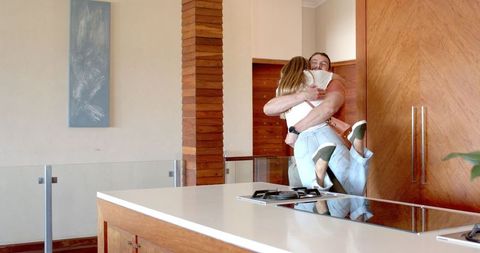 Joyful Embrace between Friends in Modern Kitchen Setting