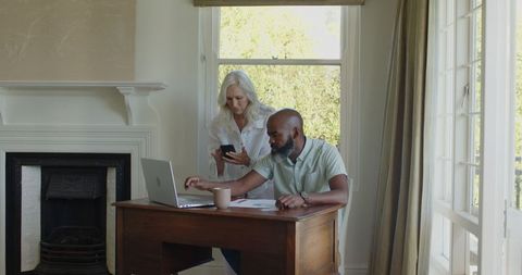 Mature couple planning wedding with laptop and smartphone at home