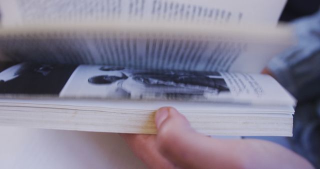 Close-up of a person flipping through the pages of a book, highlighting the act of reading and studying. Ideal for use in educational materials, library promotions, learning resources, and literacy campaigns.