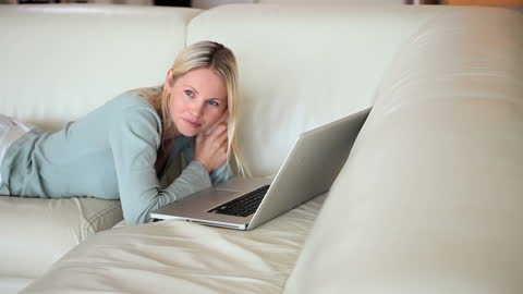 Woman Relaxing on Sofa with Laptop at Home