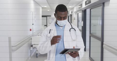 Physician tapping tablet and reviewing patient data in modern hospital corridor
