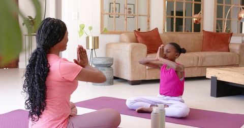 African american mother and daughter meditating together at home practicing mindfulness