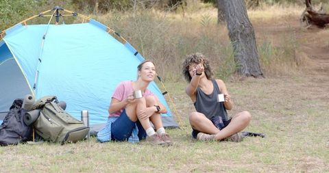 Women Enjoying Camping Adventure with Tent and Binoculars