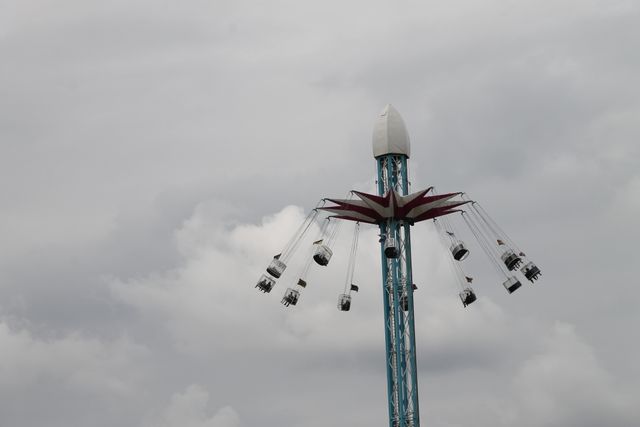 This visual of a high swing ride against a cloudy sky is suitable for themes related to entertainment, outdoor activities, and carnival festivities. It can be utilized in blogs about amusement parks, marketing materials for festivals, tourism brochures, or any promotional material for family outings and excitement-filled weekend getaways.