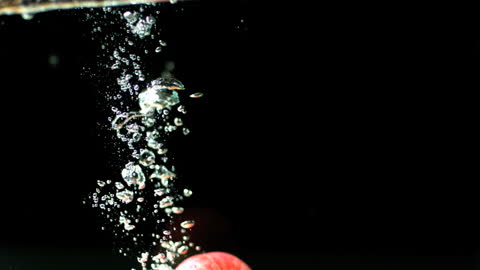 Red Apple Splashing Underwater with Bubbles in Motion