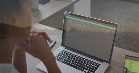 Professional Woman Analyzing Code on Laptop in Modern Office