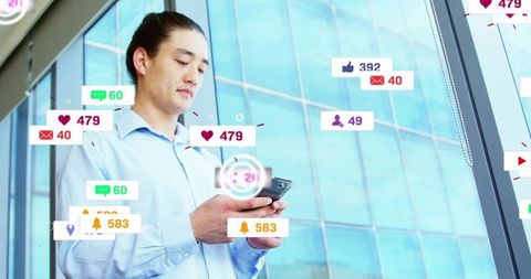 Japanese businessman checking smartphone with social media notifications in glass office