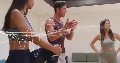 Male fitness coach leading small group stretching and mobility session in indoor studio