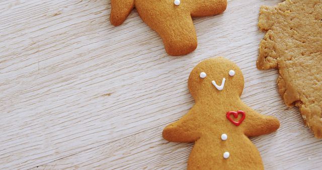 A festive gingerbread cookie with a red heart icing decoration sits on a wooden surface. - Download Free Stock Photos Pikwizard.com