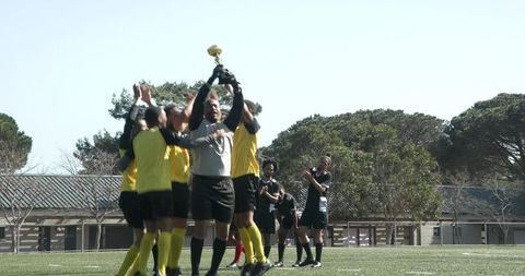 Male soccer team celebrates victory holding golden trophy