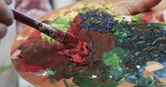 A biracial female artist mixes paints on a palette in her studio, embodying creative life. - Download Free Stock Photos Pikwizard.com